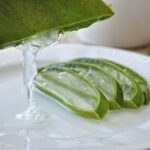 Immagine di una foglia di aloe vera con gel estratto e strumenti per il taglio.