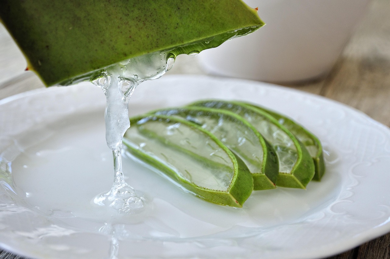Immagine di una foglia di aloe vera con gel estratto e strumenti per il taglio.